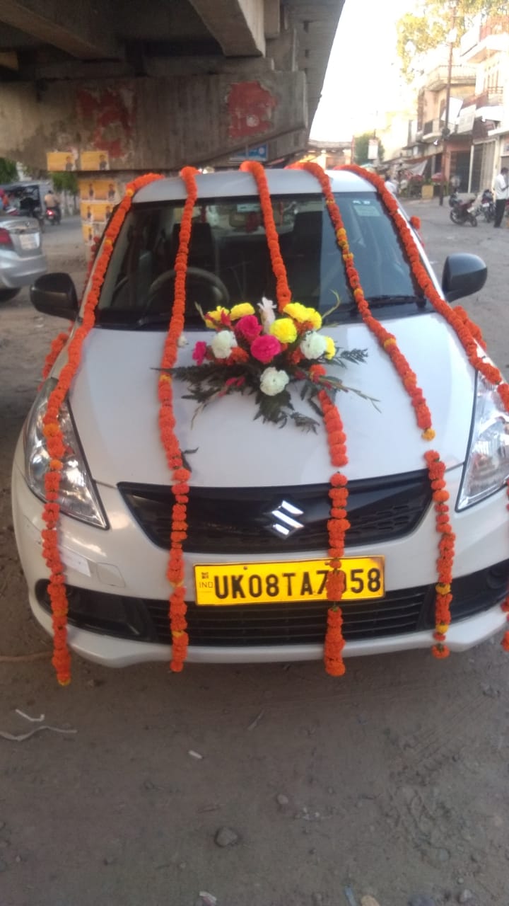 Decorated Swift Dzire with traditional orange and yellow flower garlands